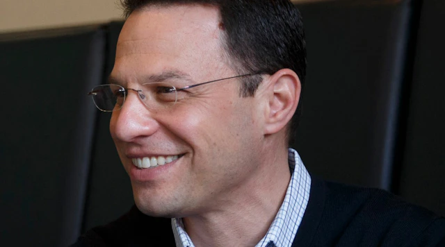 Man smiling off to the side with glasses and a sweater