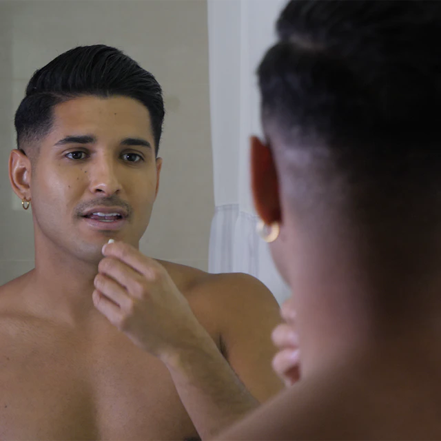 Man looking in the mirror without a shirt on.