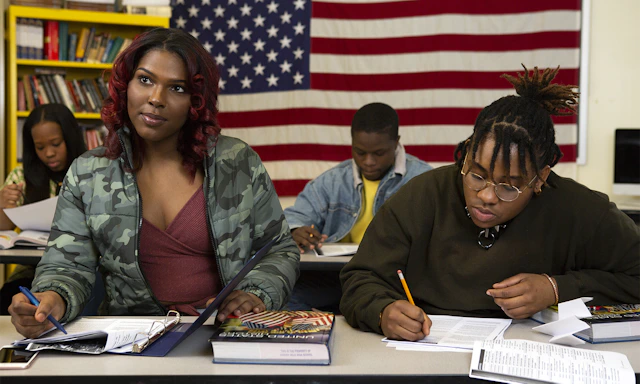 A transfeminine student sitting next to a non-binary student in class