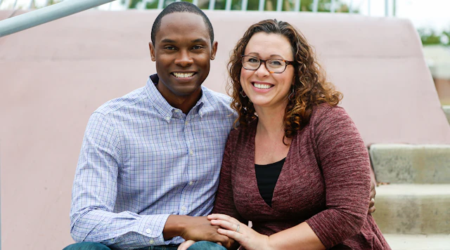 Inter-racial couple with arms around each other.