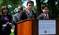 Group photo of people on stage with speaker behind podium at the 2011 Faith Leaders for Equality event.