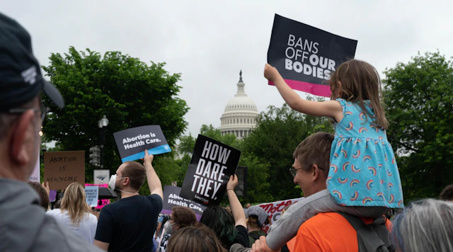 Crowd photo taken at the Roe v Wade Bans of Our Bodies march in DC. People holding HRC signs and specifically a girl on her father's shoulders.