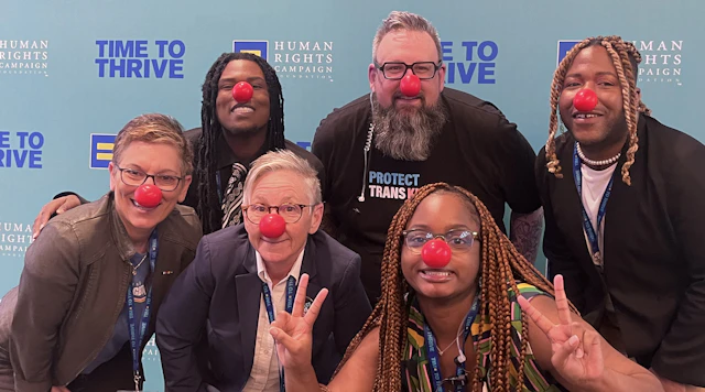 All Children All Families and Youth Well-being team posed with red noses in front of a HRC Time to thrive backdrop