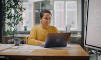 Femme presenting person using a laptop at a desk.