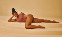 Image of a Black female presenting person laying provocatively on stairs.