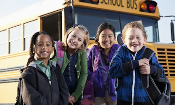 4 kids in front of a school bus